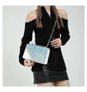 Detail of white chain shoulder bag with blue and yellow textured abstract pattern