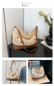 Detail of straw bucket bag with strawberry embroidery and brown leather contrast