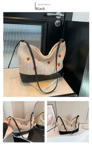 Detail of woven straw bucket bag with strawberry patterns and black leather base