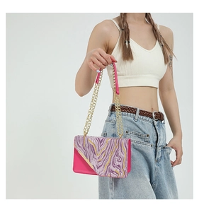 Fashionable magenta chain bag with purple marble texture shown on a female model