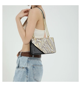 Detail of a color-block shoulder bag with textured weave and metallic chain strap