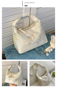 Detail view of beige silk jacquard handbag with floral patterns and bead zipper pull
