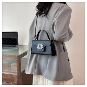 Detalle de elegante bolso de cuero negro con una hebilla cuadrada de diamantes de imitación