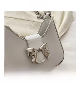 Détail d'un sac demi-lune blanc avec boucle nœud en métal argenté et bandoulière