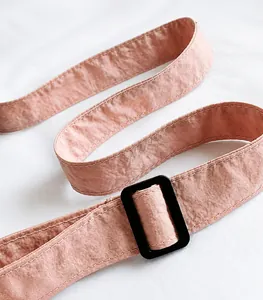 Detail eines verstellbaren pfirsichfarbenen Schultergurts aus Nylon mit schwarzer Schnalle
