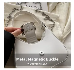 Gros plan d'un sac blanc avec boucle magnétique argentée et chaîne métallique épaisse