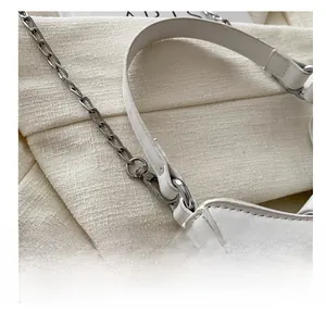 Détail du crochet en métal argenté et de la bandoulière réglable sur un sac blanc