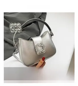 Close-up of a silver crescent underarm bag with a large sparkling rhinestone buckle
