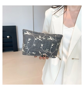 Bordado detallado en bolso de encaje gris oscuro con motivos florales y cremallera de metal