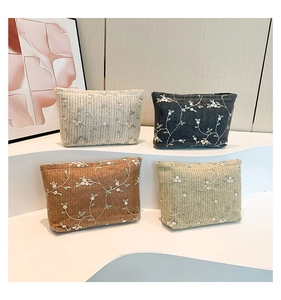 Detail of four floral embroidered lace storage bags in cream, black, tan, and light green