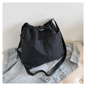 Detail der schwarzen wasserdichten Nylon-Beuteltasche mit Kordelzug auf Denim-Jacke