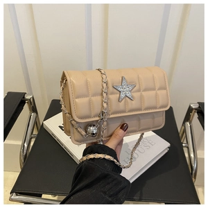 Detail of beige quilted crossbody bag with a rhinestone star emblem and silver chain