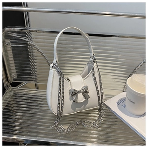 Détail du sac à main en cuir blanc avec un nœud métallique argenté et bandoulière