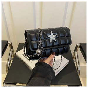Detail view of black quilted chain bag with a crystal-encrusted star on the flap