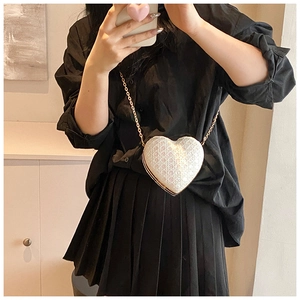 Détail du sac à bandoulière blanc en forme de cœur avec motif matelassé et chaîne