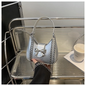 Détail du sac hobo argenté métallisé avec nœud chromé et poignée en cuir blanc