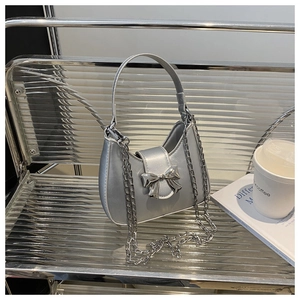 Détail du sac hobo argenté métallisé avec nœud chromé et bandoulière chaîne sur support
