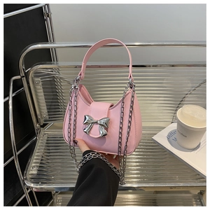 Détail du sac à main rose avec un grand nœud en métal argenté et des chaînes amovibles
