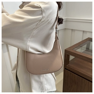 Detail van minimalistische beige hobo-tas met kiezellederen textuur en modieuze tekst