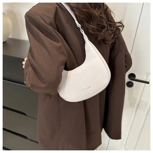 Detailweergave van een witte halvemaanvormige schoudertas van leer met lychee-patroon