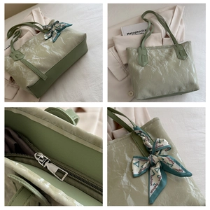Detalle del bolso tote verde claro con textura arrugada y pañuelo de seda decorativo