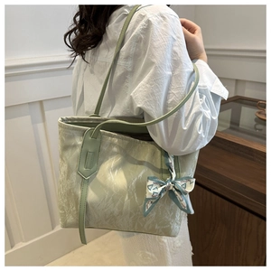 Detalle de bolso tote plisado verde claro con un pañuelo de moda en el asa