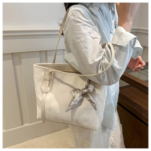 Detalle de un bolso tote blanco minimalista con textura natural y pañuelo decorativo