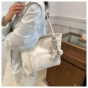 Bolso tote blanco elegante con textura de mármol y detalle de pañuelo de seda visto en modelo