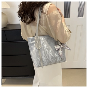 Detalle de bolso tote gris plateado con textura arrugada y pañuelo de moda en el asa