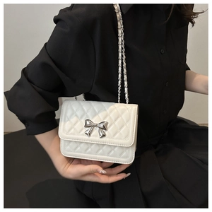 Detailaufnahme der weißen Stepptasche mit silberner Schleifenschnalle und Kettenriemen
