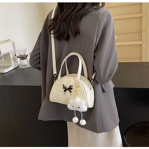 Sac bandoulière beige chic avec boucle papillon et breloque nuage sur tenue décontractée
