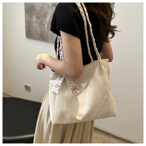 Detail of minimalist cream tote bag with woven straps and geometric silk scarf