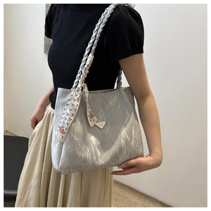 Close-up of pleated grey tote bag with woven handles and decorative floral silk scarf