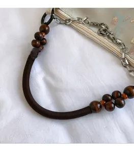 Detail of wooden bead handle with fabric wrap and metal chain on retro tote bag