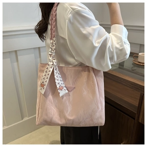 Detail of pink pleated tote bag featuring rope handles and a decorative silk scarf