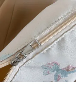 Detail of zinc alloy zipper pull and butterfly embroidery on the satin silk tote bag