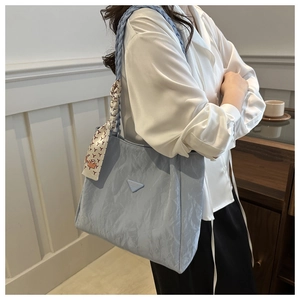 Light blue tote bag with silk scarf detail and woven shoulder strap on a white shirt