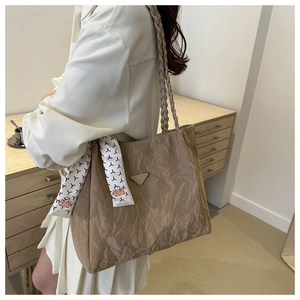 Detail of light khaki tote bag with pleated texture and decorative silk scarf accessory