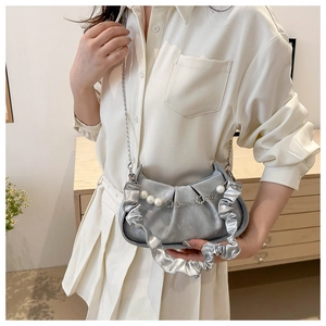 Detalle del bolso medialuna plateado plisado con cadena de perlas y asa con volantes