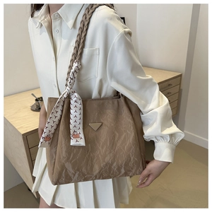Detail of khaki tote bag with pleated texture and woven strap worn by a model