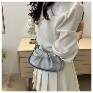 Detalle del bolso de media luna plisado plateado con cadena de perlas y flores