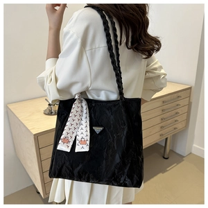 Detail of black tote bag featuring crinkled texture, silk scarf, and triangle logo