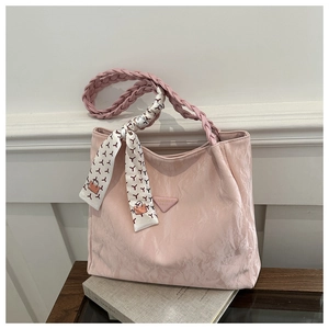 Close-up of pink pleated tote bag featuring a woven handle and floral silk scarf detail