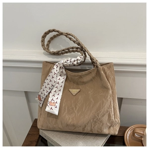 Detail of latte-colored textured tote bag with braided handle and silk scarf accessory
