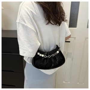 Detalle del bolso de media luna negra con cadena de flores de perlas y correa metálica