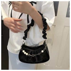 Detalle de bolso nube negro plisado con cadena de perlas y adornos metálicos florales