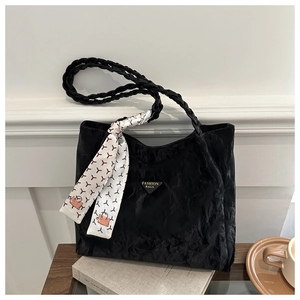 Close-up of black pleated tote bag with woven handles and decorative floral silk scarf