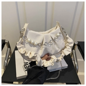 Detalle de bolso medialuna plisado crema con cadena de perlas y correa plateada
