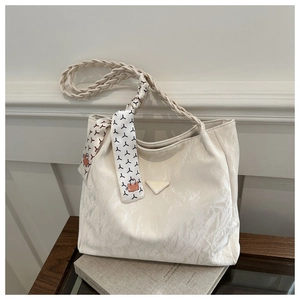 Close-up of white pleated tote bag with woven handle and decorative floral silk scarf
