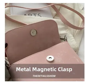 Detalle del cierre magnético de plata de alta calidad en un bolso tipo cubo de cuero rosa